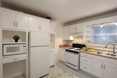 Spacious all white kitchen opens up to living space.