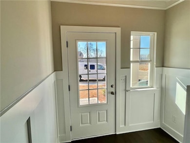 Doorway featuring ornamental molding, dark hardwoo