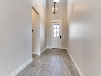 Doorway to outside with wood finished floors, a high ceiling, and a chandelier