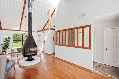 Living area with wood finished floors, a wood stove, and baseboards