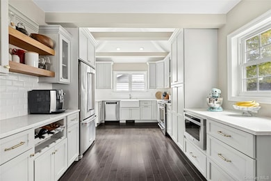 Kitchen with glass insert cabinets, open shelves, premium appliances, dark wood-style floors, and light stone counters