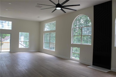 Unfurnished room with wood finished floors, a ceiling fan, and baseboards