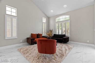 Living area featuring high vaulted ceiling, light marble finish flooring, and recessed lighting