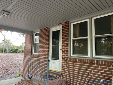 Property entrance featuring covered porch and brick siding