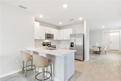 Kitchen featuring appliances with stainless steel finishes, light countertops, a kitchen breakfast bar, a peninsula, and white cabinetry