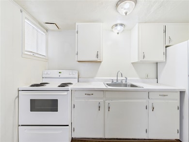 Kitchen featuring white appliances, light countertops, and white cabinets
