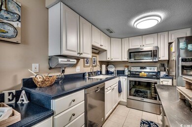 Kitchen with dark countertops, appliances with sta