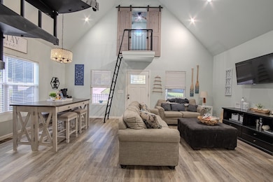 Living area featuring high vaulted ceiling, light wood-style floors, and recessed lighting