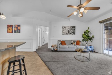 Living area with lofted ceiling, light carpet, plenty of natural light, ceiling fan, and light tile patterned flooring