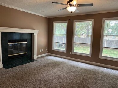 Unfurnished living room featuring crown molding, a textured ceiling, carpet, a tile fireplace, and ceiling fan