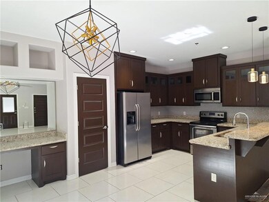 Kitchen with kitchen peninsula, stainless steel appliances, hanging light fixtures, and sink