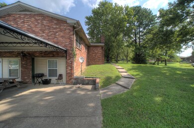 Mature trees, walkway, and side entry into home.