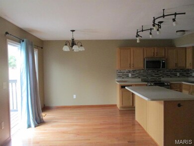 Kitchen with appliances with stainless steel finishes, light wood-style flooring, decorative backsplash, light countertops, and a chandelier