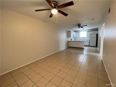 Unfurnished living room with light tile patterned flooring, a ceiling fan, and baseboards