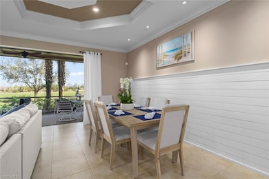 Tiled dining space with a tray ceiling, crown mold