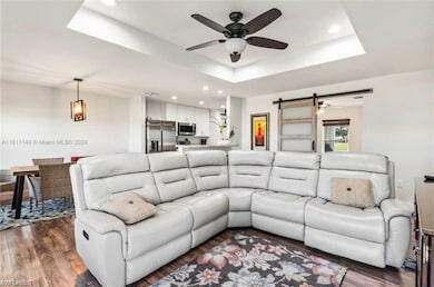 Spacious great room featuring an elegant coffered ceiling, seamlessly flowing into the dining area and overlooking a modern kitchen with white cabinetry, stainless steel appliances, and beautiful granite countertops.