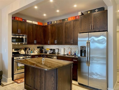 Kitchen with appliances with stainless steel finishes, backsplash, wood cabinets, a center island, and recessed lighting