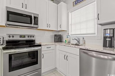 Kitchen featuring sink, white cabinetry, light sto