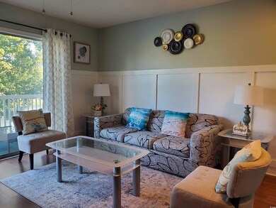Living area featuring wood finished floors, a decorative wall, and a wainscoted wall