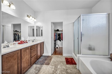 Full bath with a spacious closet, a shower stall, double vanity, and a bath