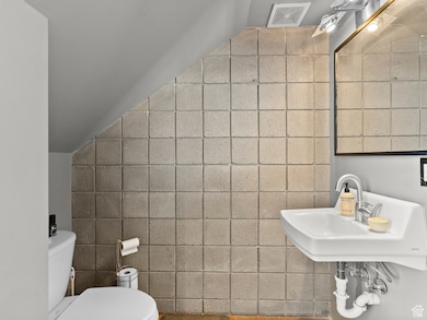Bathroom featuring tile walls and toilet