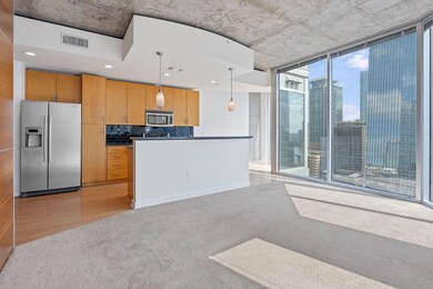 Kitchen with appliances with stainless steel finishes, decorative light fixtures, a wall of windows, light carpet, and backsplash