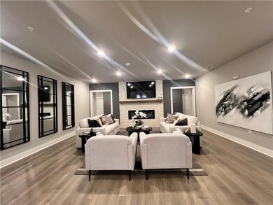 Home theater with wood finished floors, a stone fireplace, and vaulted ceiling
