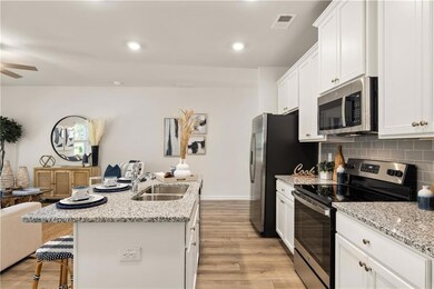 Kitchen featuring stainless steel appliances, a sink, a kitchen breakfast bar, white cabinets, and light wood-type flooring