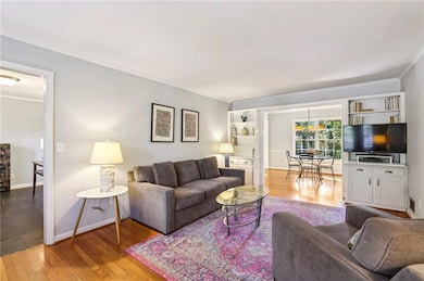Living room featuring light wood-style flooring and crown molding