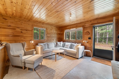 Living room featuring plenty of natural light, concrete floors, wood walls, and wood ceiling