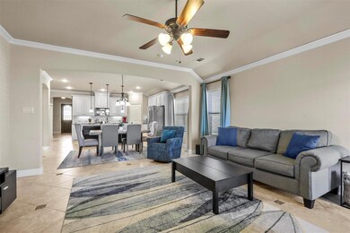 Tiled living room featuring ceiling fan, crown mol