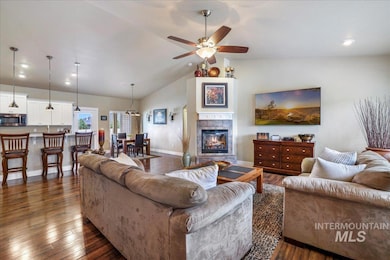 Living room with ceiling fan, vaulted ceiling, dark wood-style floors, a fireplace, and recessed lighting