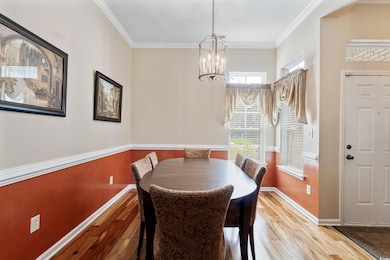 Dining area featuring wood finished floors, crown molding, and a chandelier