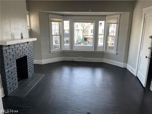 Unfurnished living room with dark hardwood / wood-style flooring and a brick fireplace