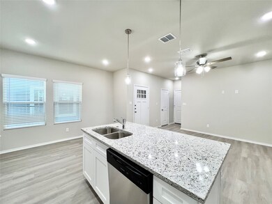 Kitchen with a ceiling fan, white cabinetry, light stone counters, light wood-style floors, and a center island with sink