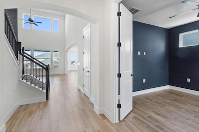 Entrance foyer with ceiling fan, stairs, light wo