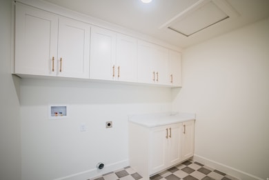 Washroom with washer hookup, hookup for an electric dryer, light floors, and attic access