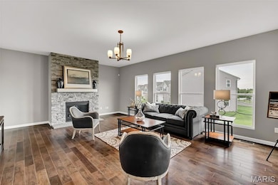 Living room with a fireplace, dark wood finished floors, and a chandelier