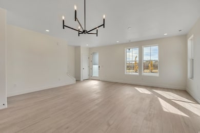 Spare room featuring light wood finished floors, a chandelier, and recessed lighting