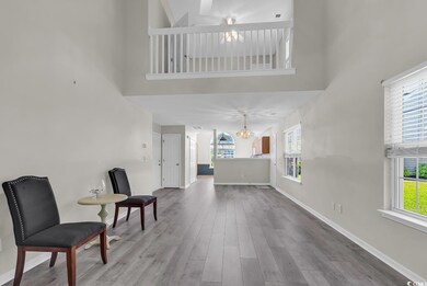 Sitting room with wood finished floors, a high cei