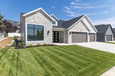 View of front of property featuring stone siding, board and batten siding, a front lawn, and a garage