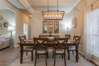 Dining room featuring crown molding, wood finished floors, and wallpapered walls