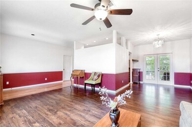 Living area with baseboards, wood finished floors, a chandelier, a ceiling fan, and french doors