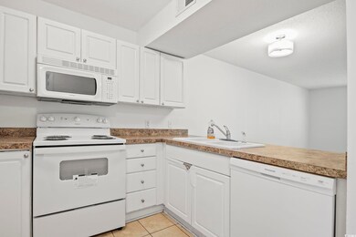 Kitchen with white appliances, light tile patterne
