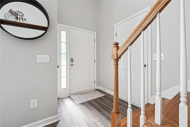 Foyer entrance featuring wood finished floors, baseboards, and stairway