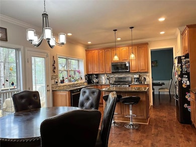 Kitchen featuring black appliances, a kitchen island, a chandelier, brown cabinetry, and recessed lighting
