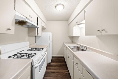 Kitchen with a textured ceiling, white appliances