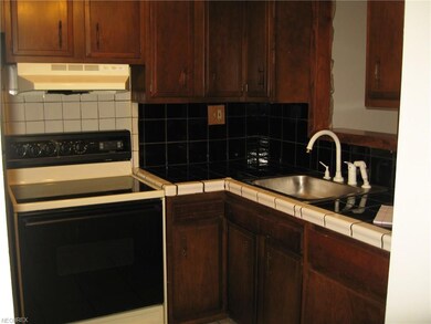 Kitchen has tile counter and stainless steel sink