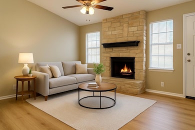 Living room with a fireplace, light wood finished floors, and ceiling fan