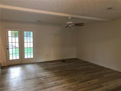 Spare room featuring plenty of natural light, a ceiling fan, wood finished floors, beamed ceiling, and baseboards